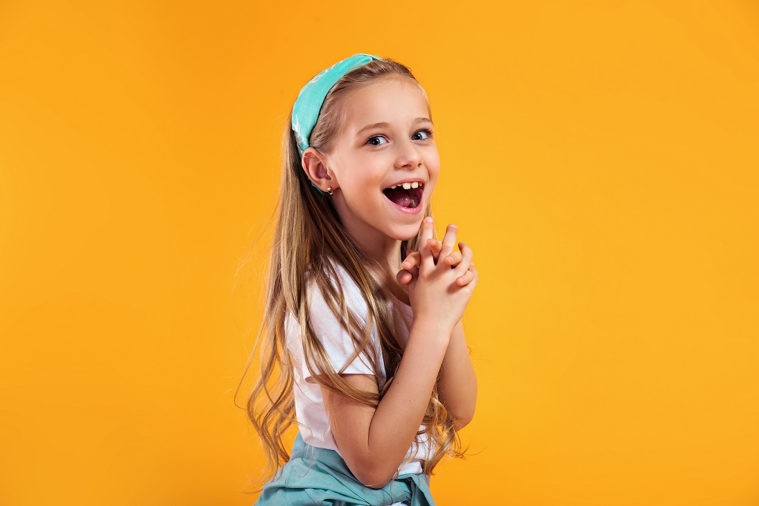Surprised Little Child Girl In Summer Clothes On A Colored Yellow Studio Background.